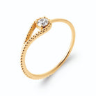 Bague boucle en goutte de fil perlé enserrant un zircon en plaqué or