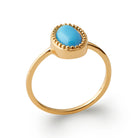 Bague cabochon ovale bleu turquoise dans une collerette perlée en plaqué or