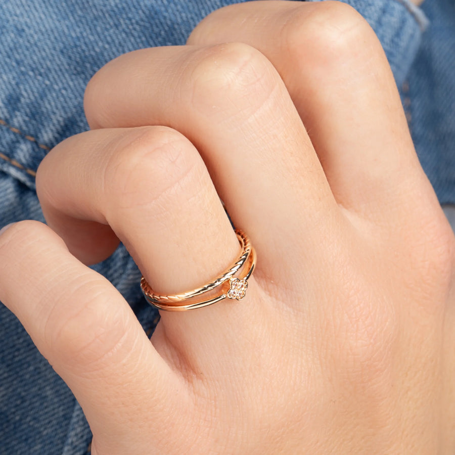 Bague double anneau torsadé surmonté d’une petite fleur de zircons en plaqué or, portée à la main