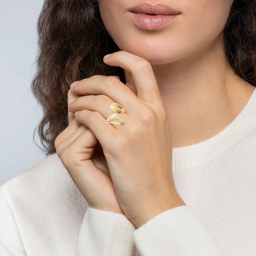 Bague double vague sculptée et striée en plaqué or, portée à la main