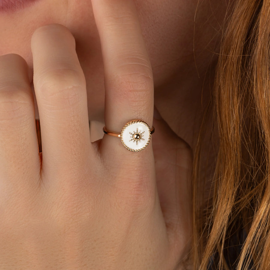 Bague goutte laquée blanche et petit soleil d’or en plaqué or, portée à la main