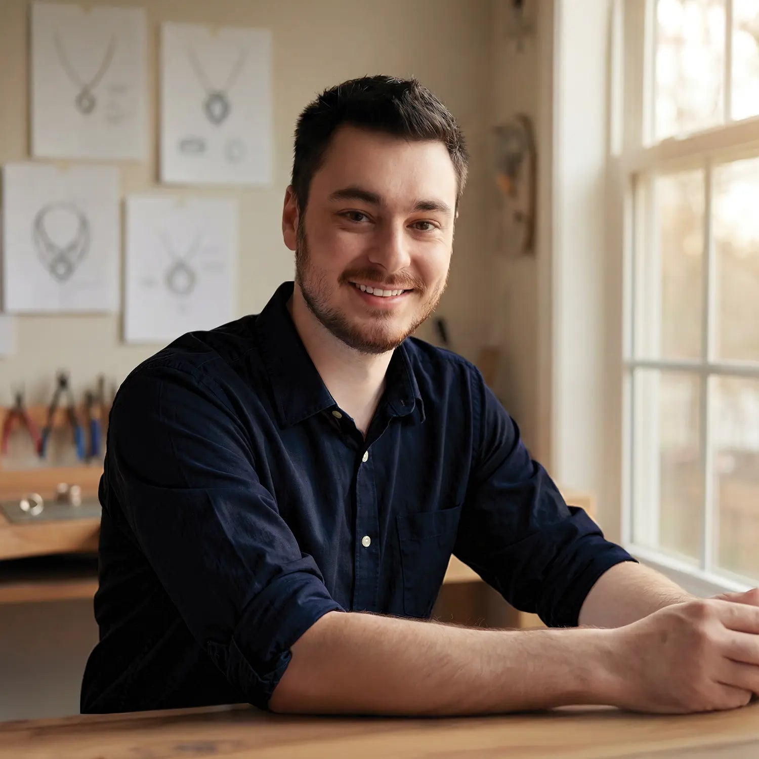 Baptiste, créateur Bajoia, examinant la délicatesse d’une bague sous la lumière de la boutique de Sèvres, illustrant l’expertise de la réparation de bijoux.