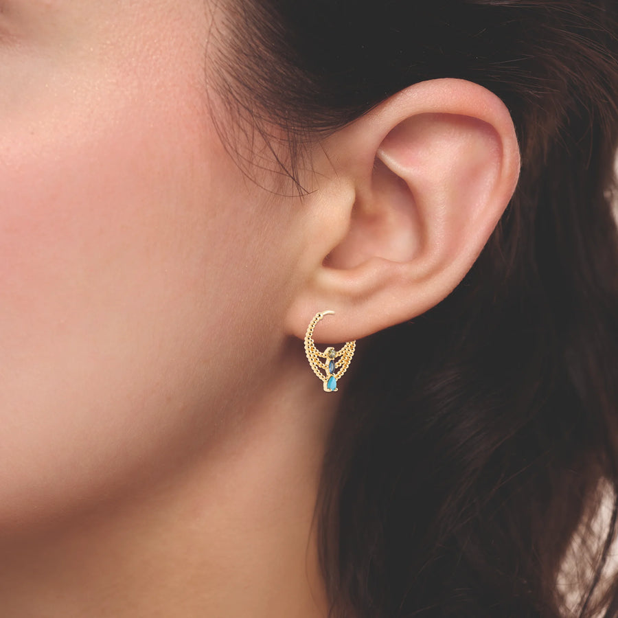 Boucles d’oreilles créoles drapées de billes et pierre bleue en plaqué or, portées à l’oreille