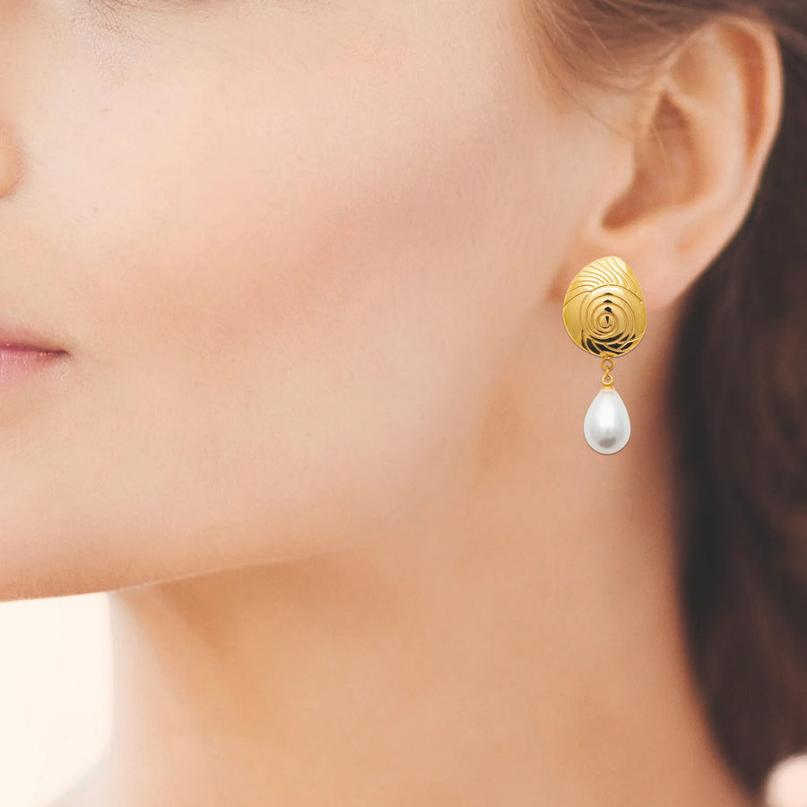 Boucles d’oreilles pendantes coquille ciselée et perle d’imitation en acier PVD doré, portées à l’oreille