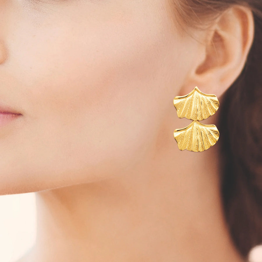 Boucles d’oreilles pendantes deux coquilles plissées en acier PVD doré, portées à l’oreille