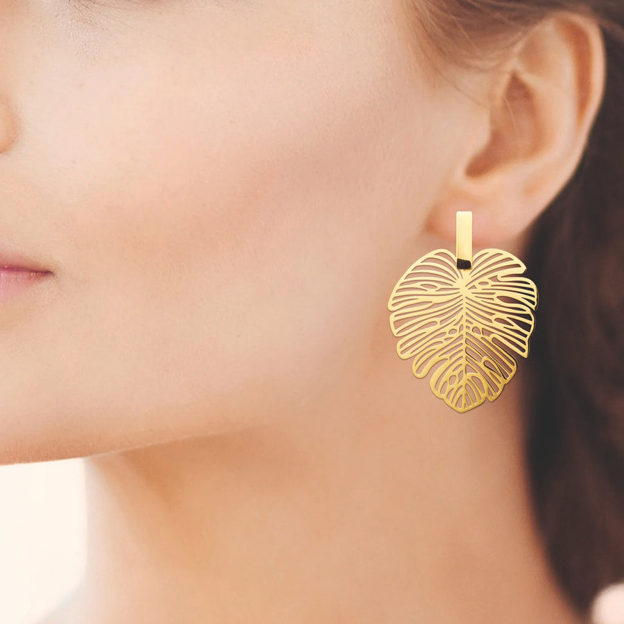 Boucles d’oreilles pendantes feuille de monstera ajourée en acier PVD doré, portées à l’oreille