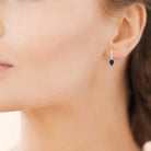 Boucles d’oreilles pendantes ligne de zircons et goutte bleu nuit en argent 925, portées par une femme