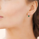 Boucles d’oreilles pendantes ligne de zircons et goutte verte en argent 925, portées par une femme