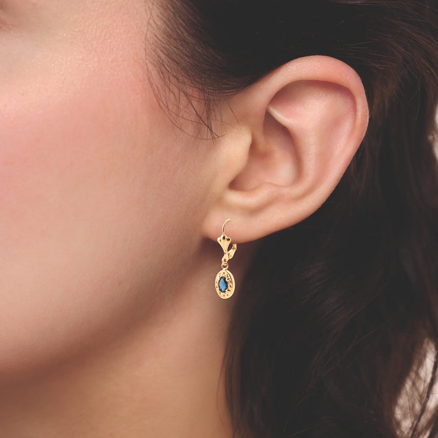 Boucles d’oreilles pendantes ovale perlé et pierre bleu nuit en plaqué or, portées à l’oreille