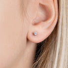 Boucles d’oreilles puces solitaire zircon quatre griffes en argent 925, portées par une femme