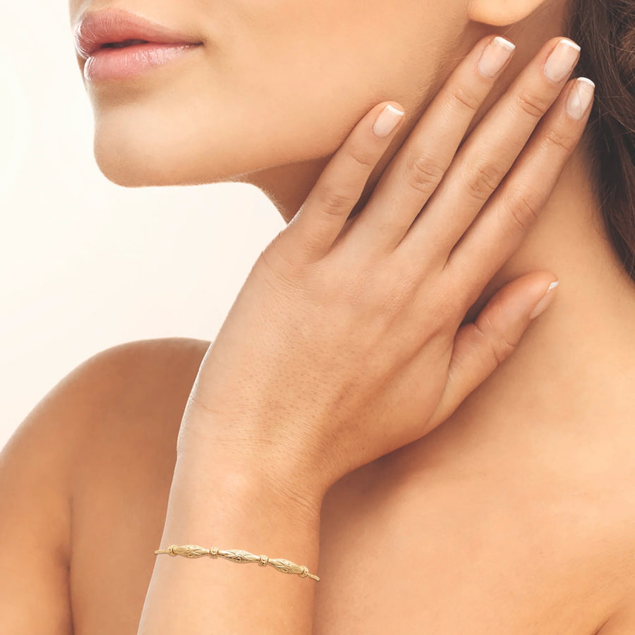 Bracelet chaîne fine navettes ciselées et anneaux striés en plaqué or, porté au poignet