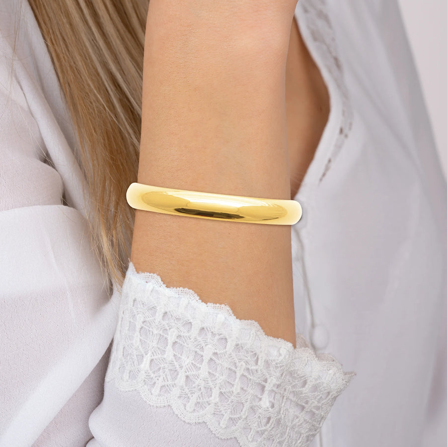 Bracelet jonc bombé lisse en acier PVD doré, porté au poignet