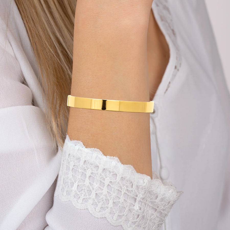 Bracelet jonc large plat en acier PVD doré, porté au poignet