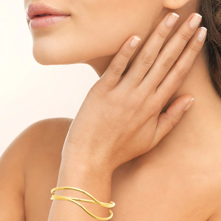Bracelet jonc ouvert trois fils ondulés en acier PVD doré, porté au poignet