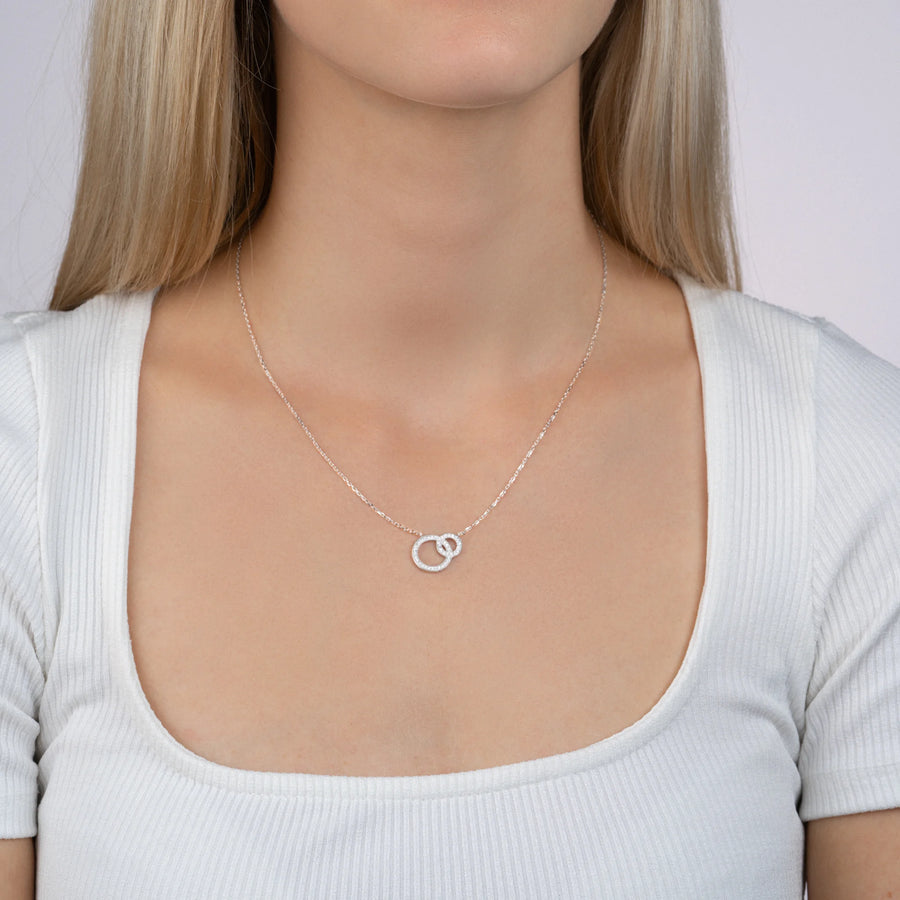 Collier deux anneaux entrelacés dont un pavé de zircons en argent 925, porté