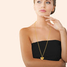 Collier long cœur bombé doré porté en sautoir sur un pull