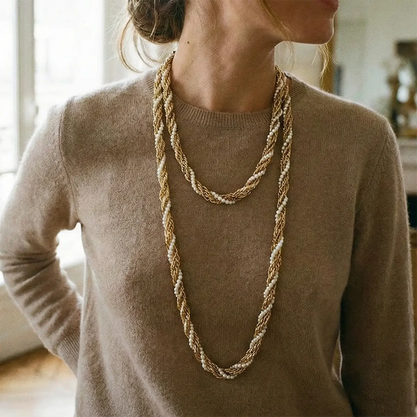 Sautoir en chaîne dorée torsadée porté doublé sur un pull beige