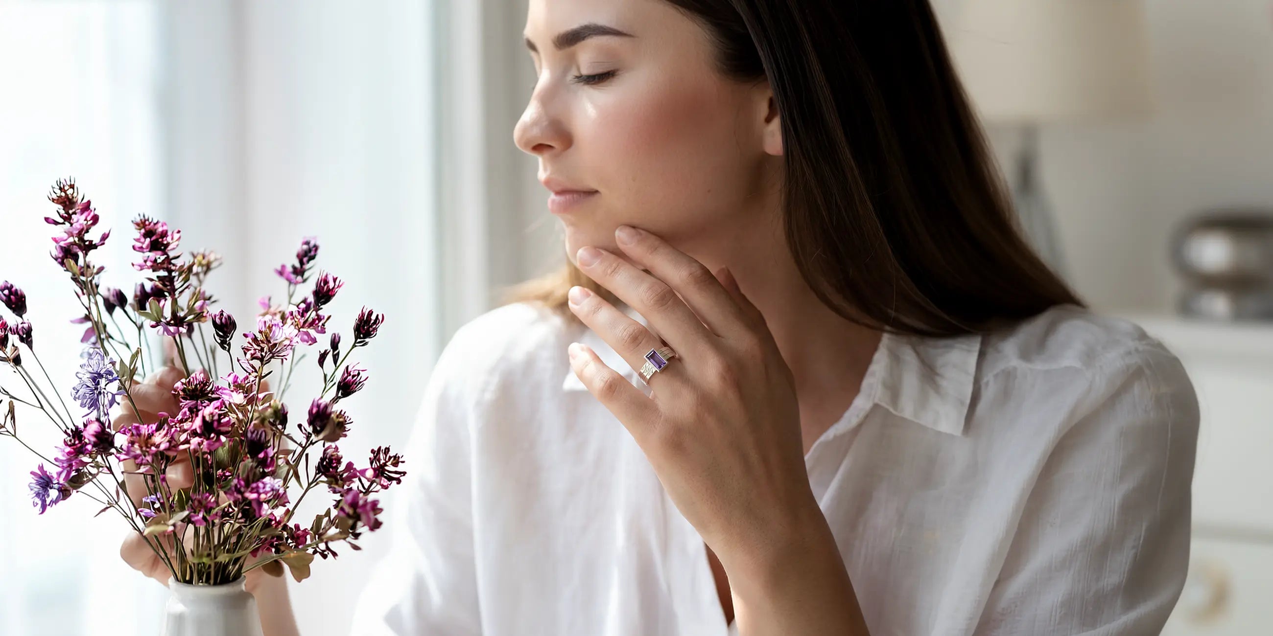 Femme portant une bague Art Déco en argent 950 sertie d'une améthyste, avec un bouquet de fleurs roses violettes